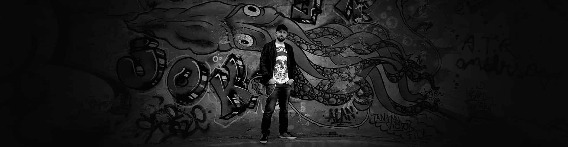 A picture of Franco in an abandoned place in front of a graffitied wall.